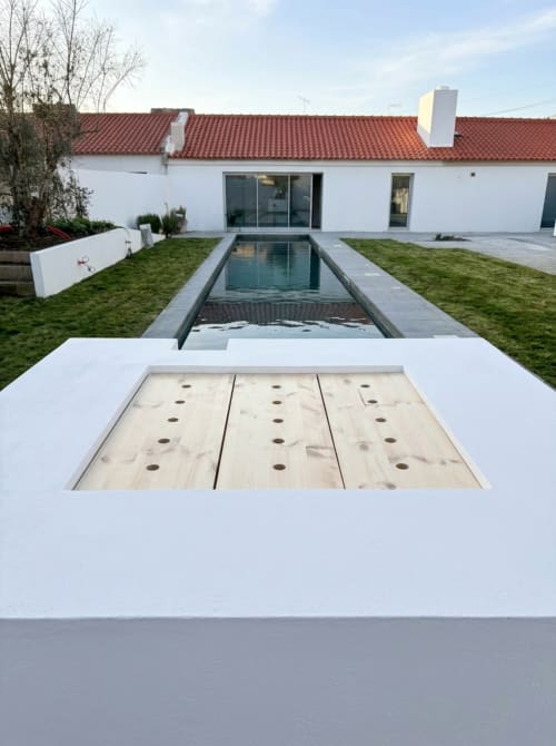 Pátio de villa moderna com jogo de cornhole em madeira, piscina retangular e casa com paredes brancas e telhado de telhas vermelhas em alentejo33