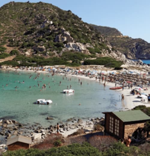 Turquoise cove beach at Hotel Ristorante Domu Incantada in Muravera with rocky cliffs and sunbathers