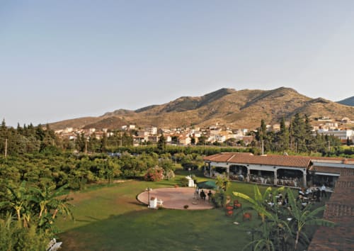 Hotel Ristorante Domu Incantada gardens and grounds overlooking Muravera with mountains, cypress trees and terracotta roofing