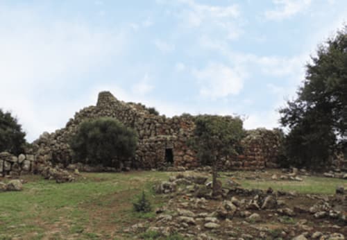 Ancient stone ruins with archway surrounded by green field near Hotel Domu Incantada in Muravera, Italy