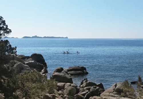 Rocky coastal view with swimmers in blue Mediterranean sea near Muravera, Italy