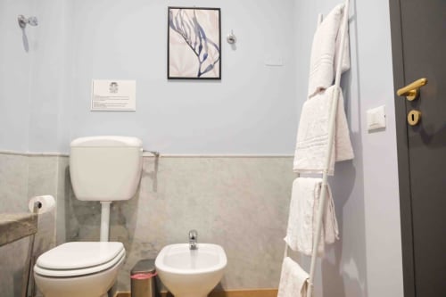 Bagno elegante di Mazzini Suites Palermo con sanitari bianchi, dettagli in marmo e morbidi asciugamani