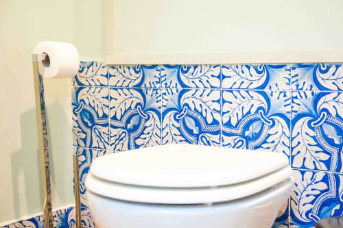 Toilette con sedile bianco nel lussuoso bagno di Mazzini Suites Palermo con piastrelle decorative blu e bianche