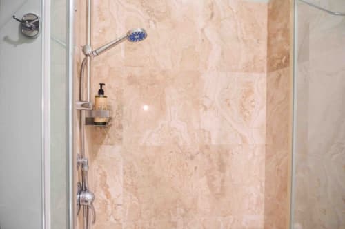 Doccia moderna con soffione blu e rivestimenti in marmo nella lussuosa camera di Mazzini Suites Palermo