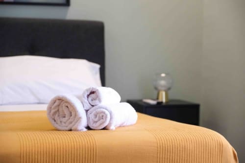 Asciugamani arrotolati disposti su un letto nella lussuosa suite di Mazzini Suites Palermo a Palermo