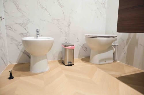 Modern bathroom display at Mazzini Suites Palermo with white bidet and toilet against marble walls