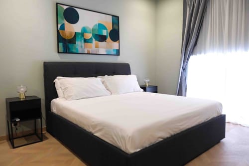 Modern bedroom at Mazzini Suites Palermo with black bed, white linens, and abstract artwork above headboard