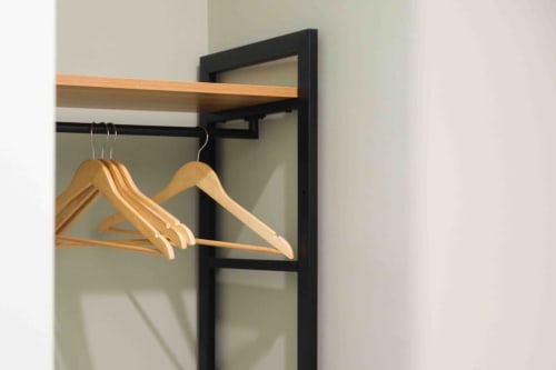 Wooden hangers on black metal frame closet at Mazzini Suites Palermo room