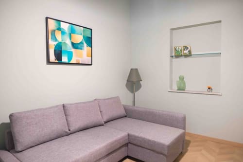 Modern living room at Mazzini Suites Palermo with gray L-shaped sofa, geometric wall art, and floating shelves with decor