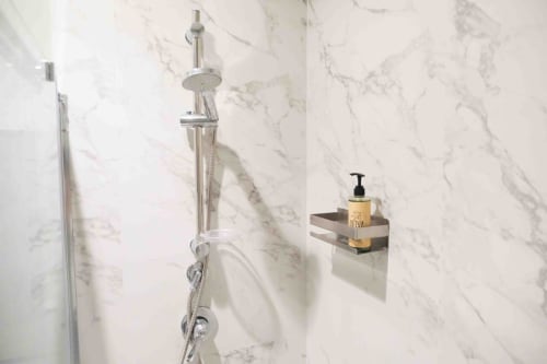 Modern shower head and marble wall with amenity bottle at Mazzini Suites Palermo, Familiare Superior room