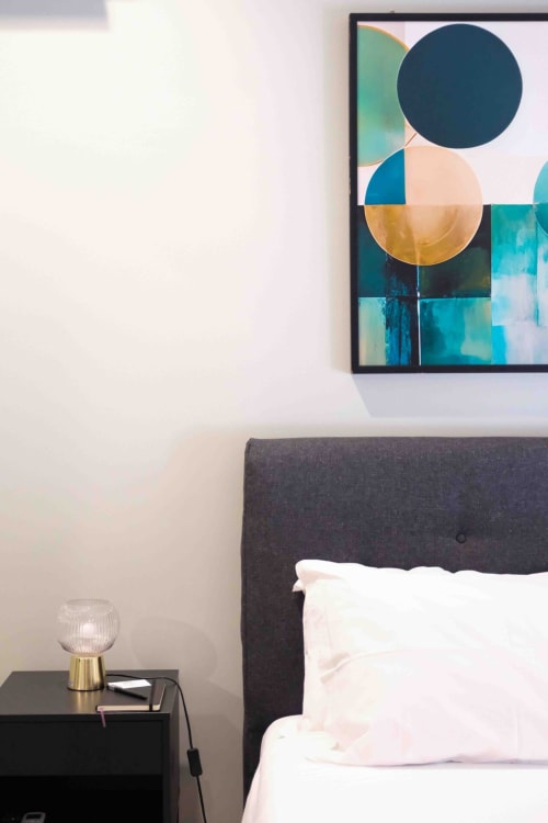 Modern bedroom at Mazzini Suites Palermo with dark headboard, white pillows, abstract geometric artwork above bed, and brass