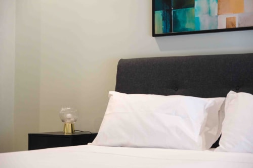 Mazzini Suites Palermo Familiare Superior room with white pillows, dark headboard, bedside lamp, and abstract artwork above