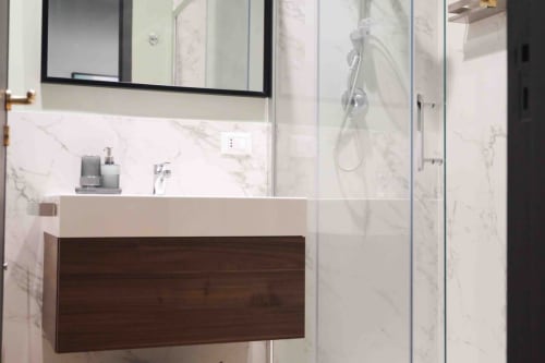 Modern bathroom at Mazzini Suites Palermo with marble walls, floating wooden vanity, and glass shower enclosure