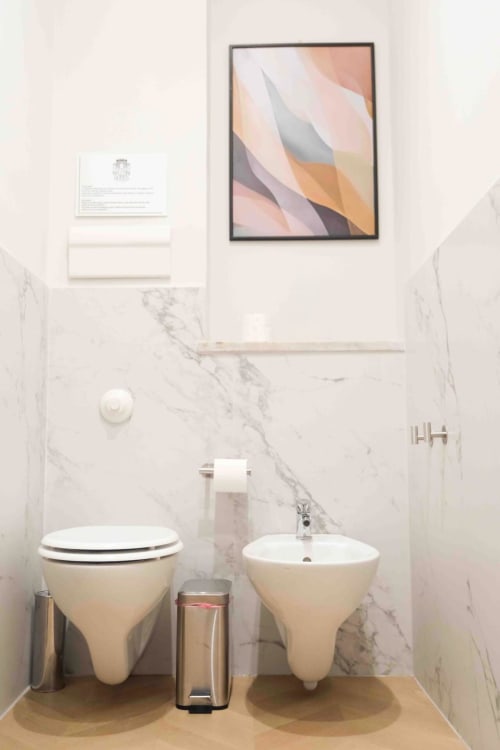 Bagno moderno alle Mazzini Suites Palermo con pareti in marmo, sanitari bianchi e arte astratta incorniciata