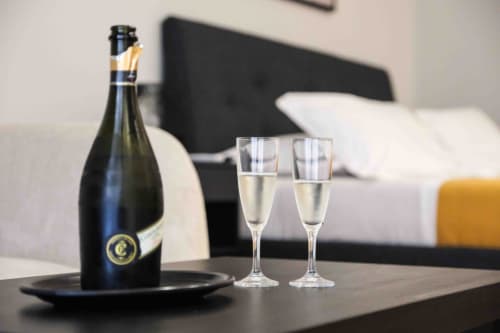 Bottiglia di champagne e due bicchieri su tavolo nella suite Romantica dell'hotel Mazzini Suites Palermo