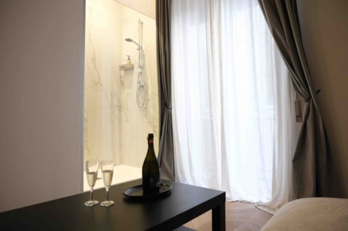 Camera Romantica presso Mazzini Suites Palermo con doccia in marmo, champagne e vista sulla città attraverso le tende