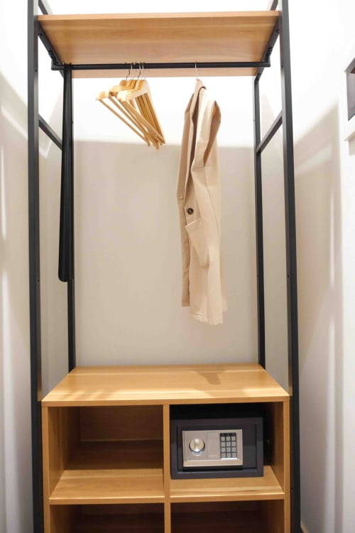Guardaroba moderno con struttura in legno e metallo nero presso Mazzini Suites Palermo, con abiti appesi e spazi di stoccaggio