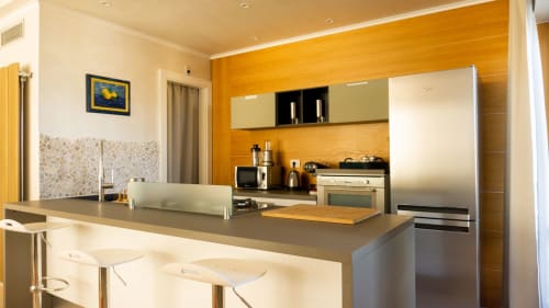 Modern luxury kitchen with wooden accent walls, stainless steel appliances, and island counter at Versilia Panoramic Luxury,