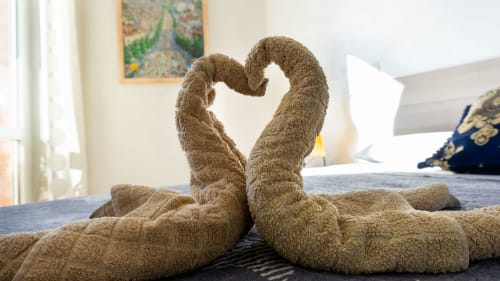 Two towels arranged in heart shape on bed at Versilia Panoramic Luxury hotel in Como, Italy