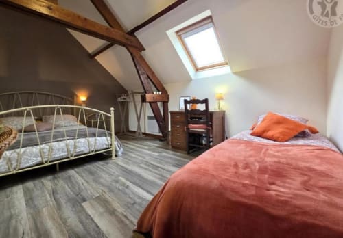 Spacious attic bedroom with two beds, wooden beams, skylight, and warm lighting at Ferme de la Forterie B&B, Verlinghem
