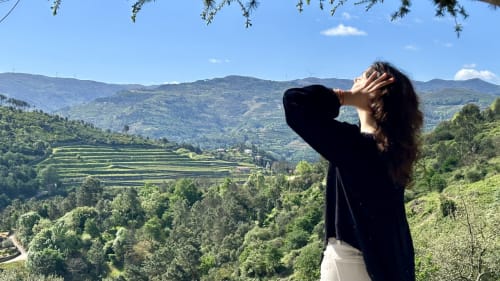 Mulher apreciando vistas panorâmicas de montanhas e vinhedos em socalcos da Quinta das Susandas em Tresouras, Portugal