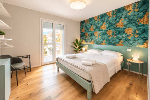 Camera moderna a Le Dimore di Giò Verde a Ortona con parete verde, letto matrimoniale, pavimenti in legno e vista sulle montagne