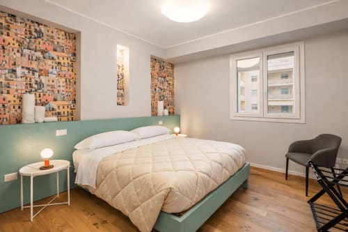 Camera da letto moderna con testata in verde salvia, biancheria bianca, pavimenti in legno e vista sulla città presso Le Dimore di Giò a Ortona, Italia