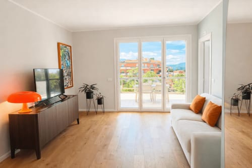 Moderno appartamento a Ortona con pavimenti in legno, divano beige, accenti arancioni e vista montagna dal terrazzo
