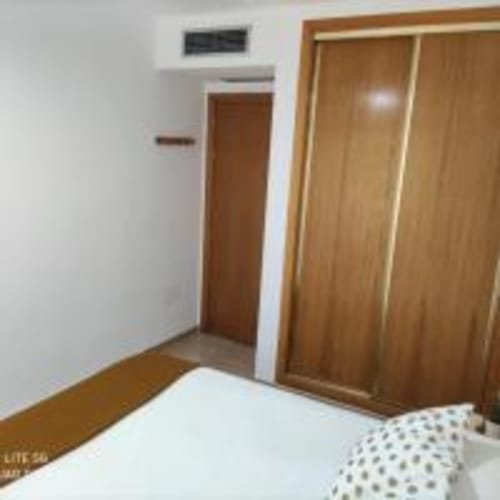 Bedroom with wooden wardrobe, bed, air conditioning, and city view at Love Rent4 Malaga apartment, Torremolinos