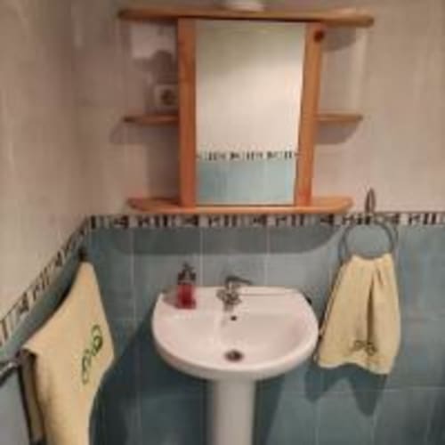 Bathroom with pedestal sink, blue tile walls, towels, and mirror at Love Rent4 Malaga apartment