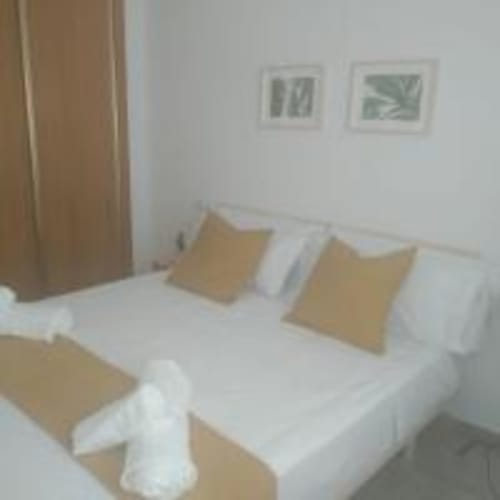 Modern bedroom with white bed, beige cushions, and botanical wall art in Love Rent4 Malaga apartment