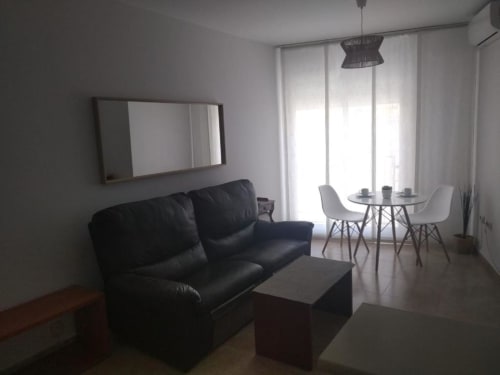 Modern apartment living room with black sofa, dining area, and city views at Love Rent4 Malaga, Torremolinos