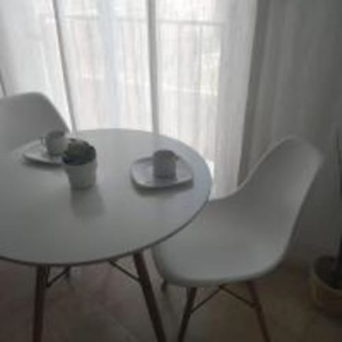 Modern dining area with round white table and chairs overlooking city views at Love Rent4 Malaga apartment