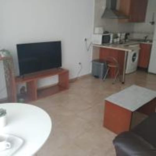 Open-plan living area in Love Rent4 Malaga apartment with TV, red furniture, kitchenette, and dining space
