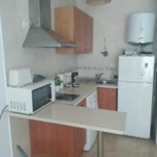 Modern kitchenette in Love Rent4 Malaga apartment with white appliances, red cabinetry, and stainless steel cooker hood