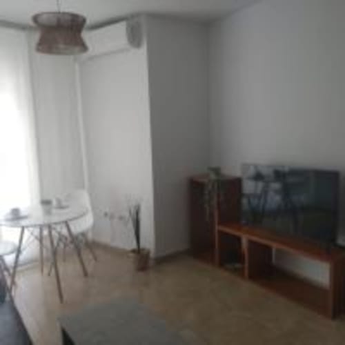 Modern apartment living room at Love Rent4 Malaga with ceiling fan, sofa, dining table, and city views in Torremolinos