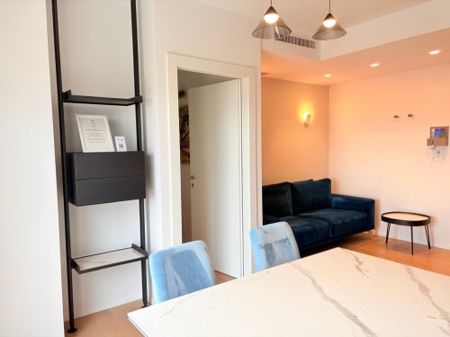 Elegante zona living dell'appartamento LE DIMORE DI GIO' a Ortona con tavolo da pranzo, divano blu, lampade a sospensione e vista sulla città
