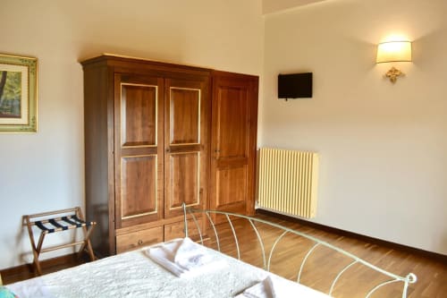 Bedroom at Agriturismo Colle Mura with wooden wardrobe, radiator, and metal bed frame in Gualdo Tadino