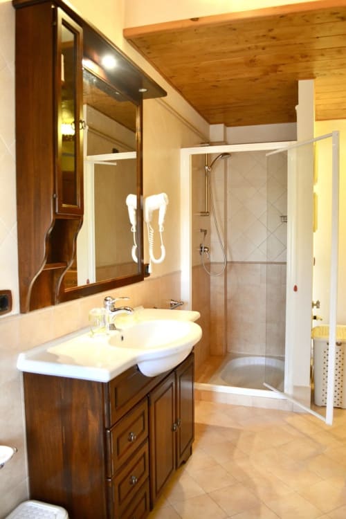 Modern bathroom with wooden vanity, mirror, and glass shower enclosure at Agriturismo Colle Mura, Le Mimose apartment in