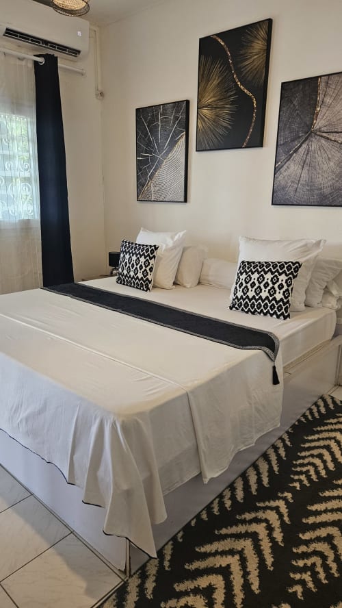 Kaz Kafe double bedroom with cream bed, black and white décor, geometric wall art, and garden view in Mamoudzou