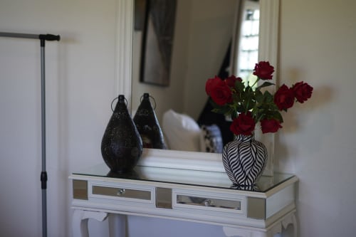 White dresser with zebra vase of red roses, black decorative lanterns, and mirror in Kaz Kafe hotel room, Mamoudzou