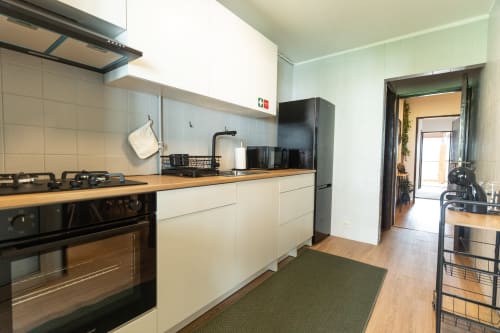 Cozinha moderna no apartamento DouroParadise, Fontelas com armários brancos, eletrodomésticos pretos, bancadas de madeira e rio