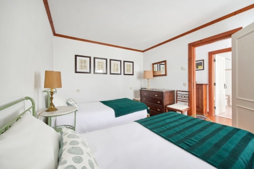 Quarto espaçoso na Quinta da Alcaidaria-Mór com camas twin, roupa de cama verde, móveis de madeira e vista para o jardim