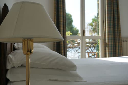 Chambre élégante avec lampe en laiton, literie blanche et balcon vue mer à l'Hôtel Beau Rivage, Alassio