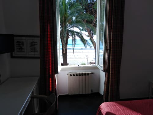 Hotelzimmer mit Meerblick im Hotel Beau Rivage in Alassio: Palme, Heizkörper und rote Vorhänge