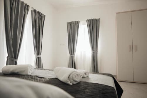 Camera moderna della Casa del Sole B&B a Foggia con tende grigie, asciugamani arrotolati e armadio