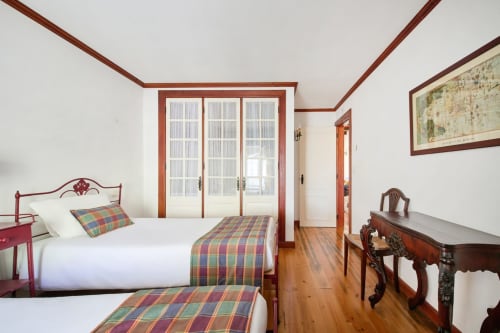 Quarto elegante da Quinta da Alcaidaria-Mór com camas gêmeas, vigas de madeira e vista para jardim em Fátima