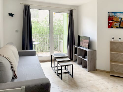 Appartement moderne au Vallon des Sources à Digne-les-Bains : canapé, TV, vue sur balcon et équipements complets.