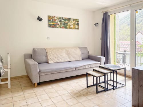 Salon moderne avec canapé gris, tables gigognes et vue sur les montagnes au Vallon des Sources, Digne-les-Bains