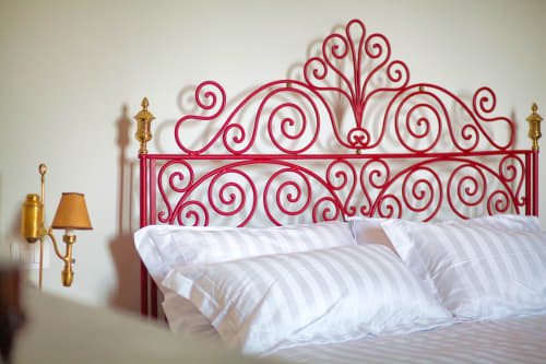 Testiera di letto in metallo rosso ornato con cuscini a righe bianche presso il boutique B&B Villa Ceci ad Andria, Italia